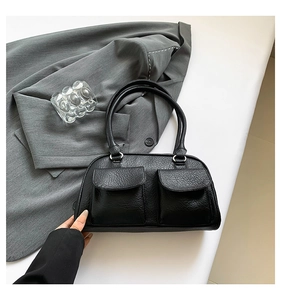 Detail of vintage black textured shoulder bag with double pockets and silver hardware