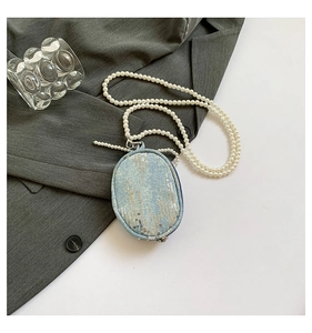 Détail du mini sac en denim bleu avec paillettes argentées et longue bandoulière en perles