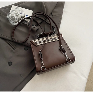 Detail of vintage dark brown backpack featuring a classic plaid patchwork design and straps