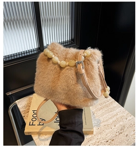 Detail of faux mink fur bucket bag with beaded handle and leather strap on marble surface