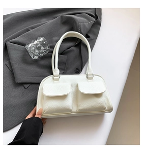Detail of white faux leather shoulder bag featuring dual front pockets and litchi texture