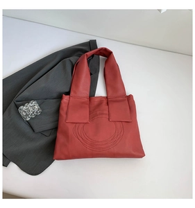 Detailed macro view of terracotta red tote bag featuring stylish circular spiral stitching