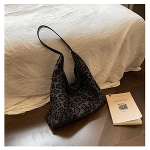 Detail of a large leopard print tote bag in grey canvas on a cozy bed background