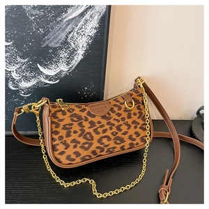 Detail of leopard print fabric and synthetic leather bag with gold chain and strap