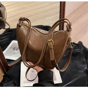 Detail of dark brown leather saddle bag with gold metal buckle and knotted strap