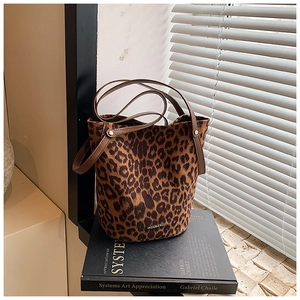 Detail of leopard print suede bucket bag with leather straps and golden rivet accents