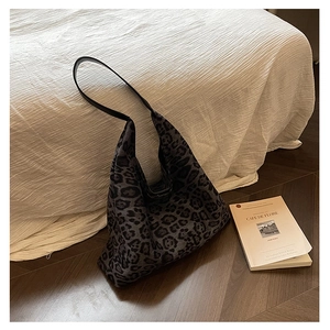 Detail shot of leopard print hobo tote bag with black leather strap on a wood floor