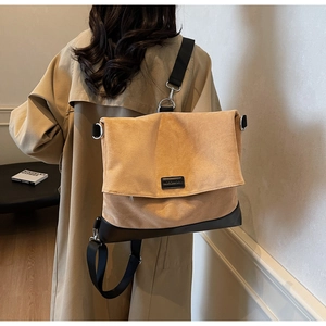 Detail view of khaki suede large shoulder bag with black strap and metallic buckles
