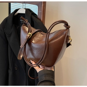 Detail of dark brown semi-circle bag with knotted strap and vintage gold metal buckle