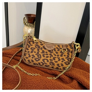 Detailed close-up of leopard print handbag with metal chain and brown leather trim accents