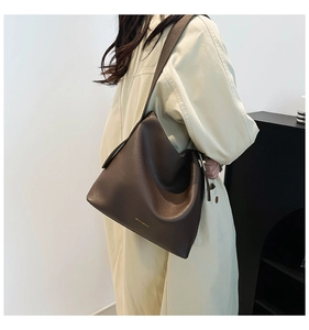 Detail of dark brown pebble leather hobo bag with wide strap and gold stamped logo
