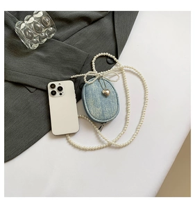 Détail du mini sac en denim bleu avec bandoulière perles blanches, nœud et cœur