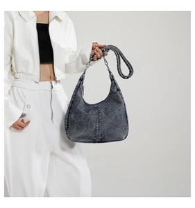 Detail view of washed denim half-moon bag with silver hardware and adjustable strap