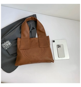 Detail view of brown PU leather tote bag with quilted circular pattern and laptop