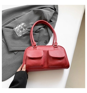 Detail of red leather shoulder bag with lychee texture and dual front pockets