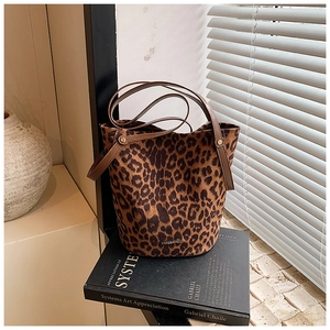 Detail of leopard print bucket bag with brown leather strap and gold metal hardware