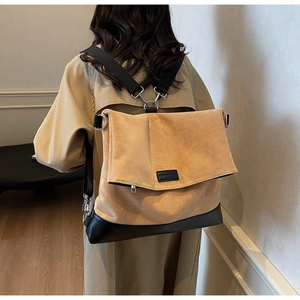 Detail of a brown suede and black leather patchwork tote with adjustable nylon shoulder strap