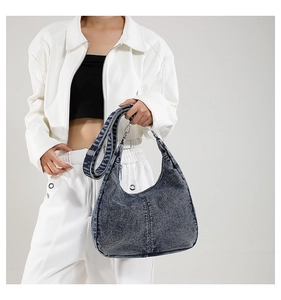 Detail of blue denim hobo bag showing vintage washed texture and adjustable wide strap