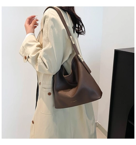 Detail of deep brown hobo bag showing pebbled leather texture and golden metal buckle