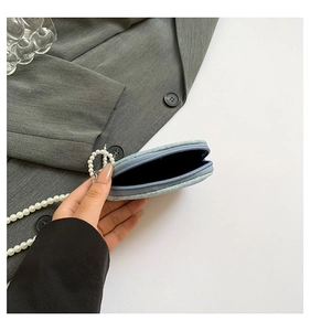 Détail intérieur d'un mini porte-monnaie en denim bleu clair avec chaîne en perles