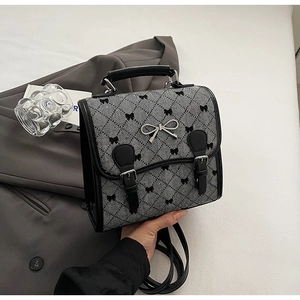 Close-up of retro checkered backpack featuring black ribbon patterns and silver bow detail