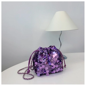 Dettaglio borsa a secchiello con paillettes viola e catena d'argento su tavolo bianco