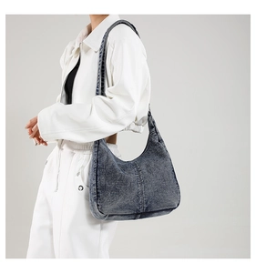 Detail of vintage washed denim hobo bag featuring white zipper and contrast stitching