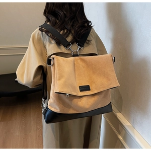 Detail of the khaki suede and black leather patchwork backpack worn by a model