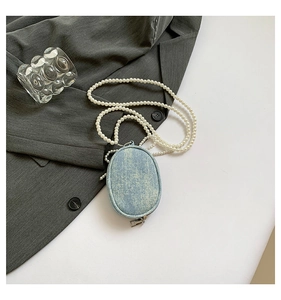 Détail d'un mini sac en denim bleu avec une élégante bandoulière en perles blanches