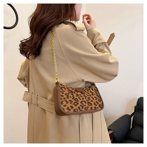 Detailed side view of leopard print baguette bag with gold chain strap on a trench coat