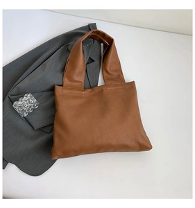 Detailed view of brown tote bag with premium leather texture and minimalist handle design