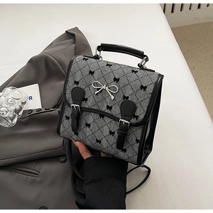 Detail of checkered fabric handbag with black bow patterns and silver metal buckle