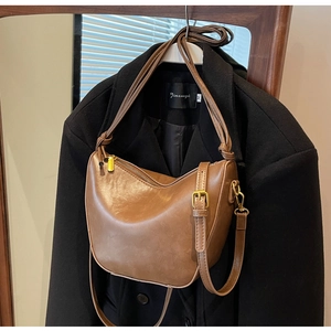 Close-up of vintage brown leather bucket bag with golden buckle and adjustable strap
