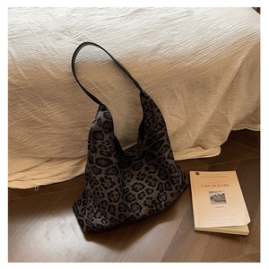 Detailed view of leopard print tote bag with black leather straps in a home setting