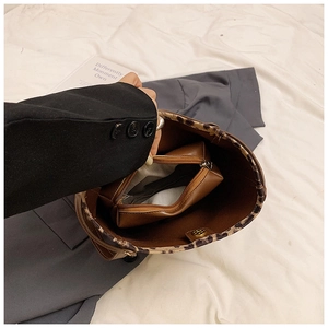 Detail view of the brown leather bucket bag interior with leopard trim and inner pouch