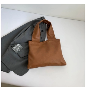 Detail view of brown faux leather tote bag with natural texture on white background