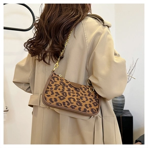 Detailed close-up of leopard print shoulder bag with gold chain strap on model