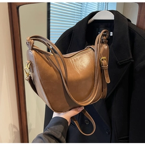 Detail of vintage brown PU leather bucket bag with gold hardware and zipper