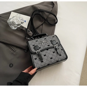 Detail of grey twill fabric handbag with black bow prints and metal buckle