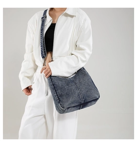 Detail view of washed navy denim hobo bag featuring wide straps and vertical stitching