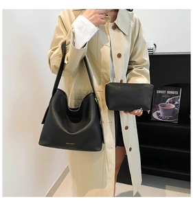 Detail of black pebbled leather bucket bag set with matching small zipper pouch on a model