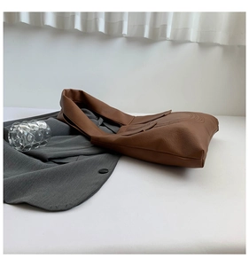 Detail of soft brown faux leather tote bag with natural texture on a white background