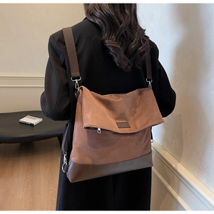 Detailed view of dark brown canvas crossbody bag with leather base worn by a model