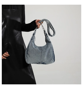 Detail of blue washed denim hobo bag with silver hardware and adjustable strap