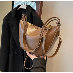 Detail of vintage brown hobo bag showing glossy faux leather texture and golden zipper