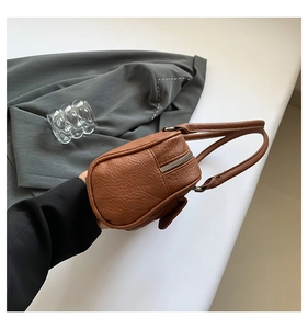 Close-up of brown litchi pattern leather shoulder bag with silver zipper and side pocket