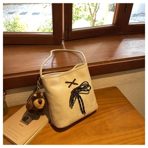 Close-up of beige suede bucket bag with brown lace-up detail and cute plush dog charm