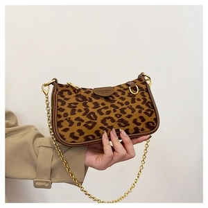 Close-up of leopard print baguette bag featuring gold chain and brown leather trim