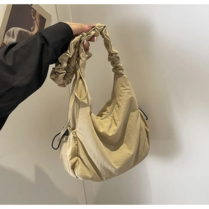 Detail van beige cloud bag met geplooid nylon materiaal en trekkoordsluiting aan zijde