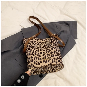 Detailed view of leopard print bucket bag with brown leather strap and gold logo